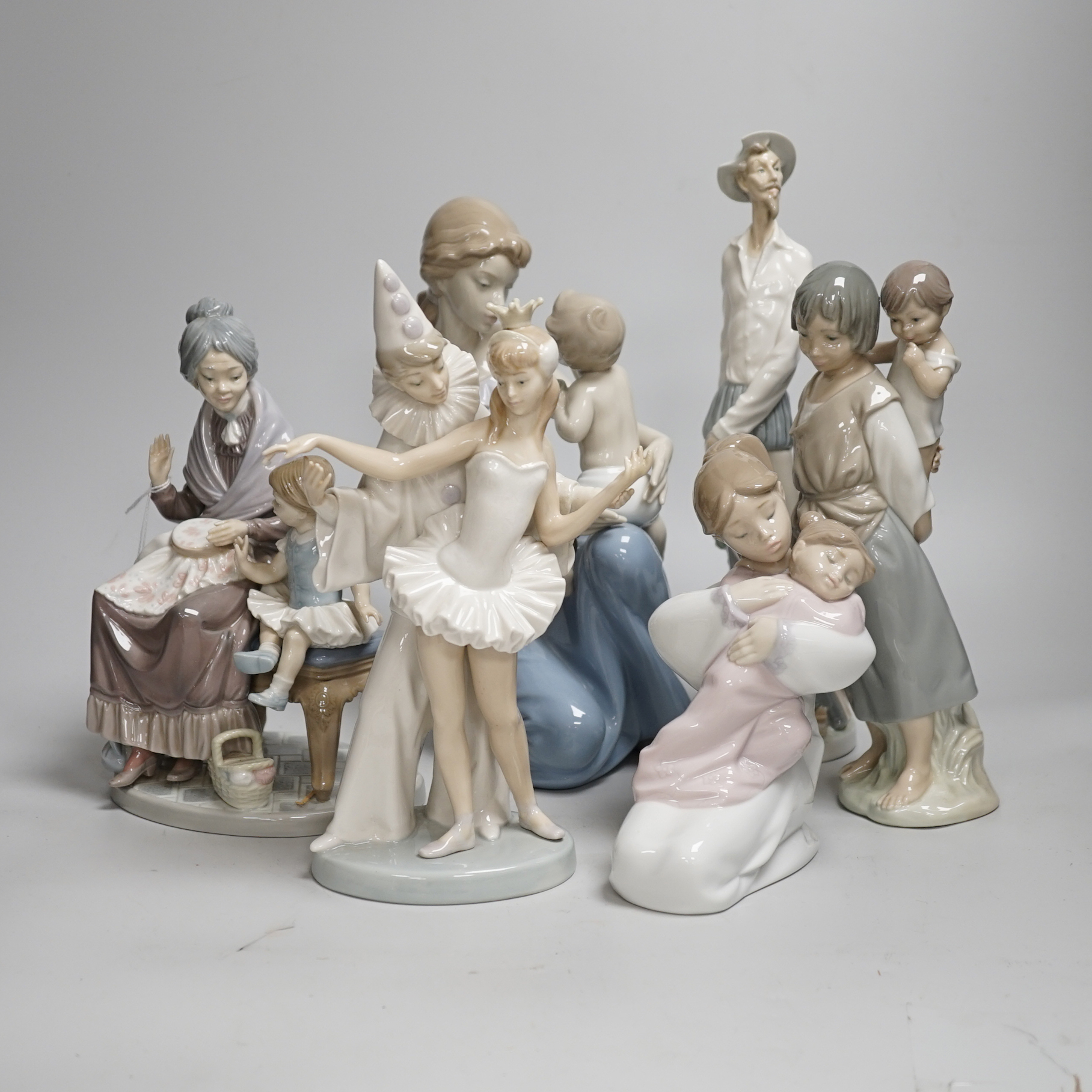 A large Lladro figure of a seated mother and child, a pierrot and ballerina, peasant woman and child, a grandmother and child and two others including a Nao example, the largest 30cm high (6)